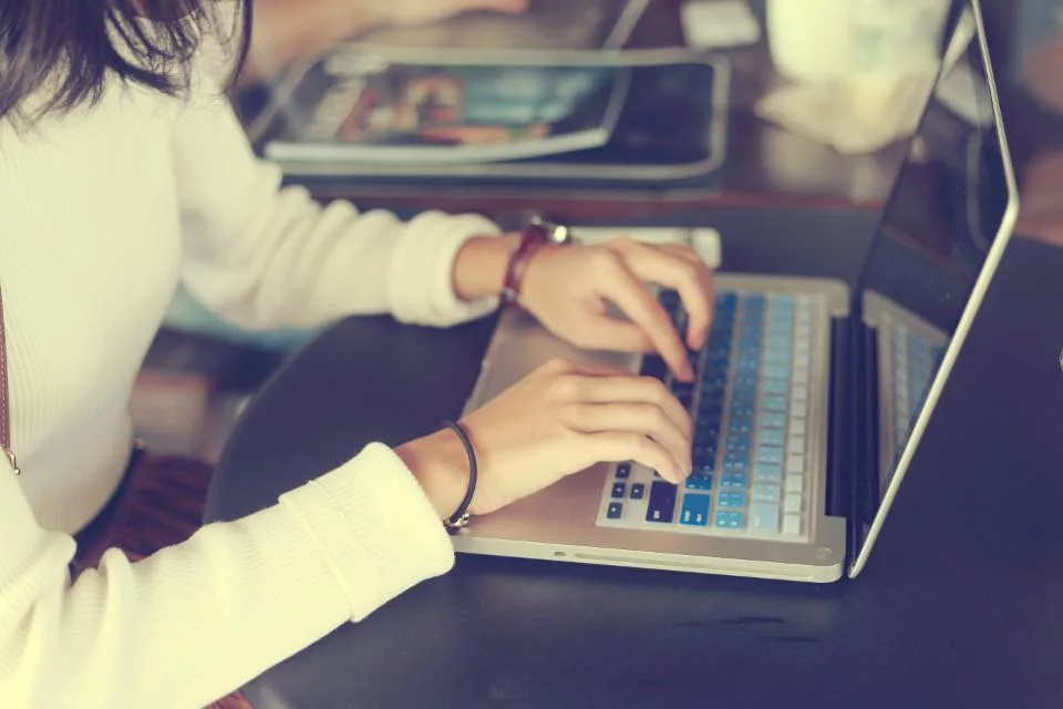 Woman typing on a laptop with a colorful keyboard at a round table