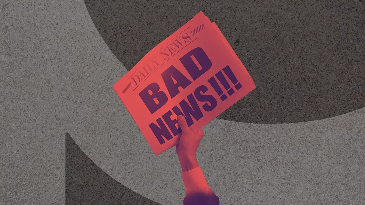 Hand holding a red newspaper with bold "BAD NEWS" headline against dark textured background.