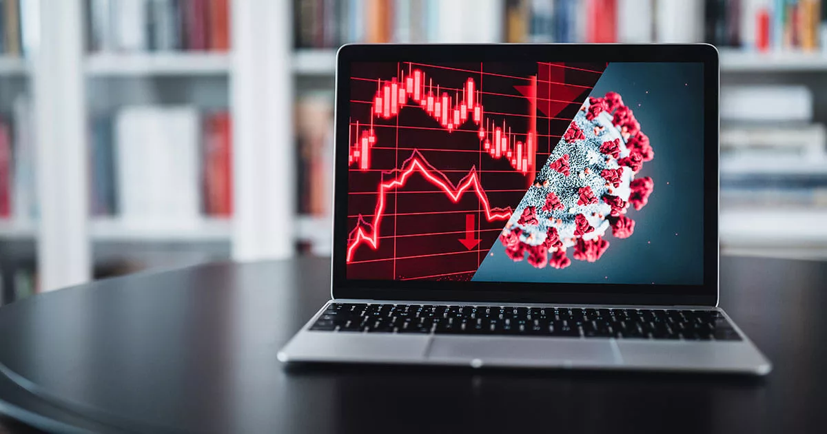 Laptop displaying COVID-19 virus and stock market graph