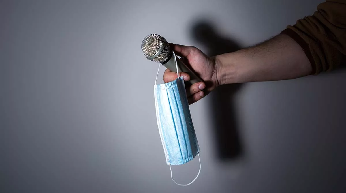 Hand holding microphone with hanging face mask
