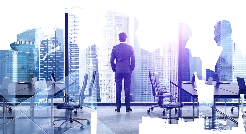Businessman overlooking cityscape from modern office with colleagues' silhouettes