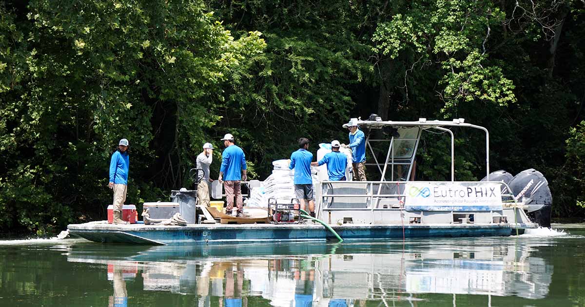 Team on pontoon applying treatments to river