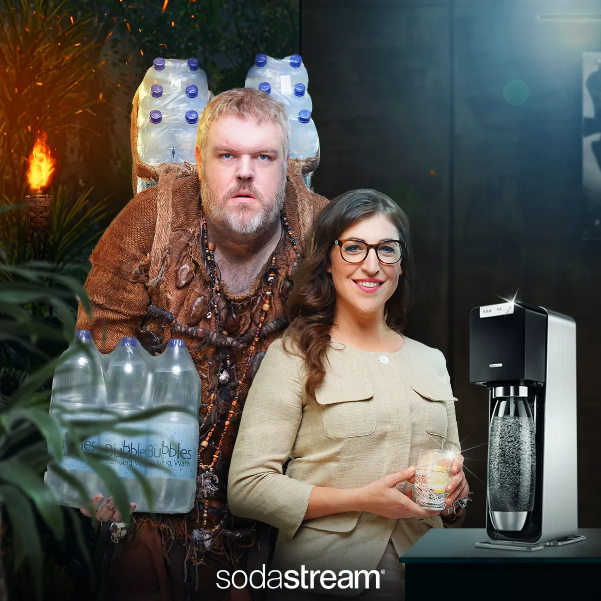 A man carrying bottles and a woman with a glass stand beside a sparkling water maker