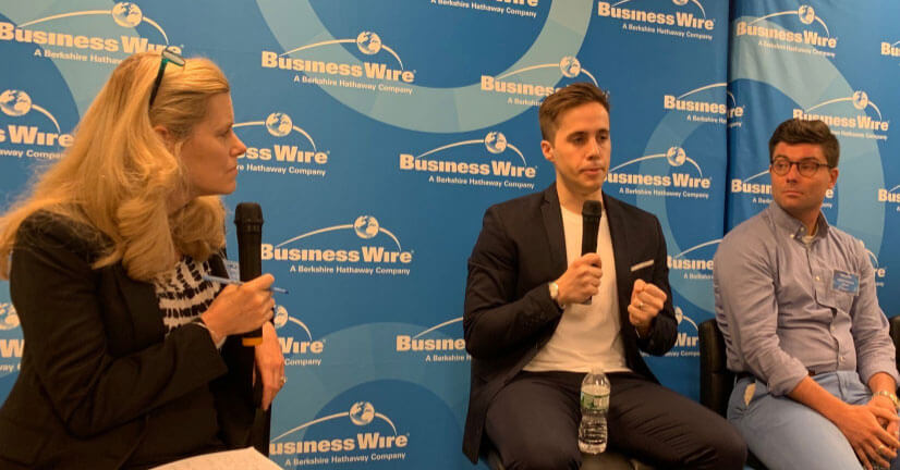 Panel discussion at Business Wire event: woman interviewing two men with microphone