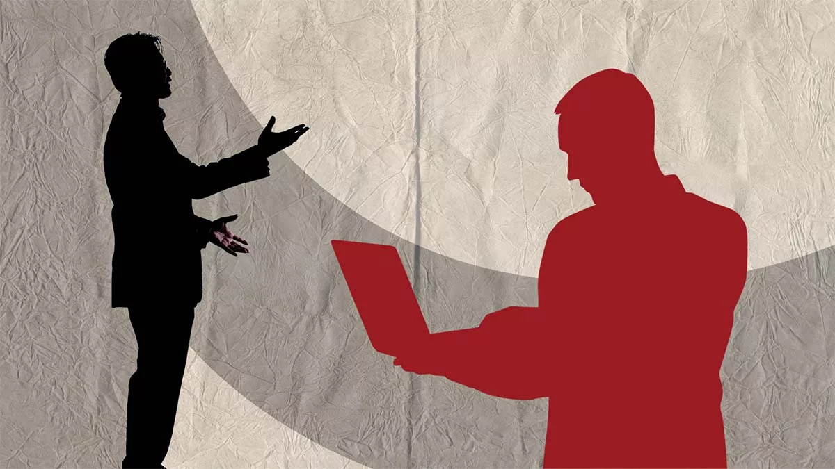 Silhouettes of a business person talking in the background of a person on a laptop