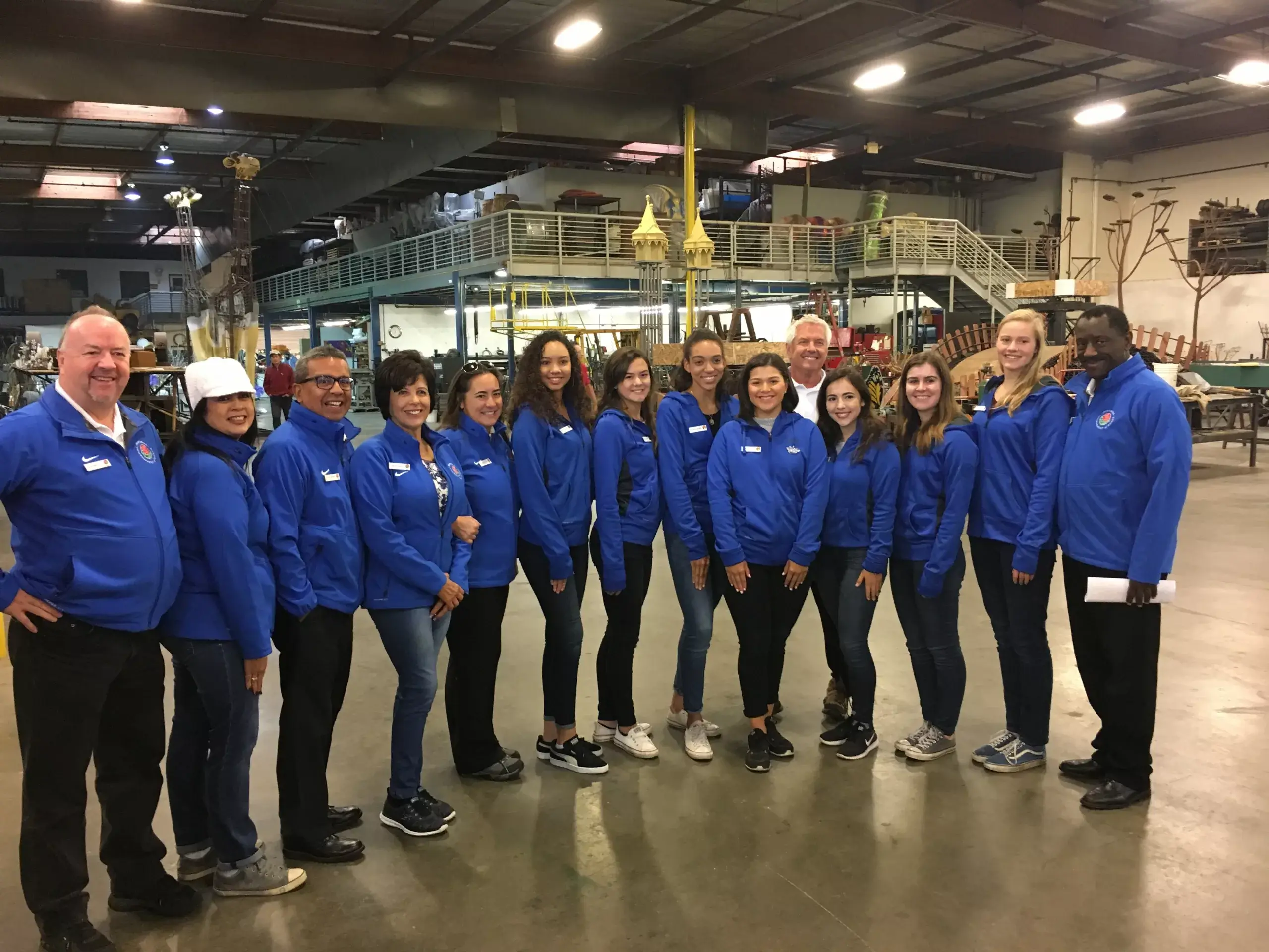 Team in blue jackets smiling in warehouse setting