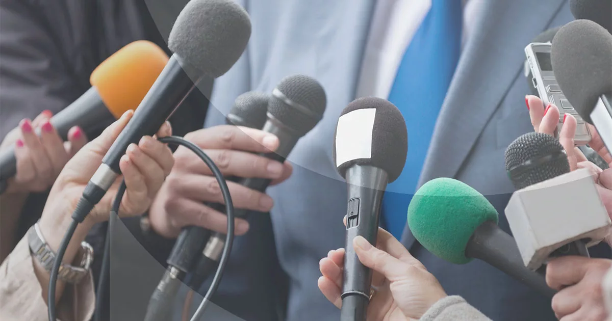 Journalists holding various microphones in a press conference