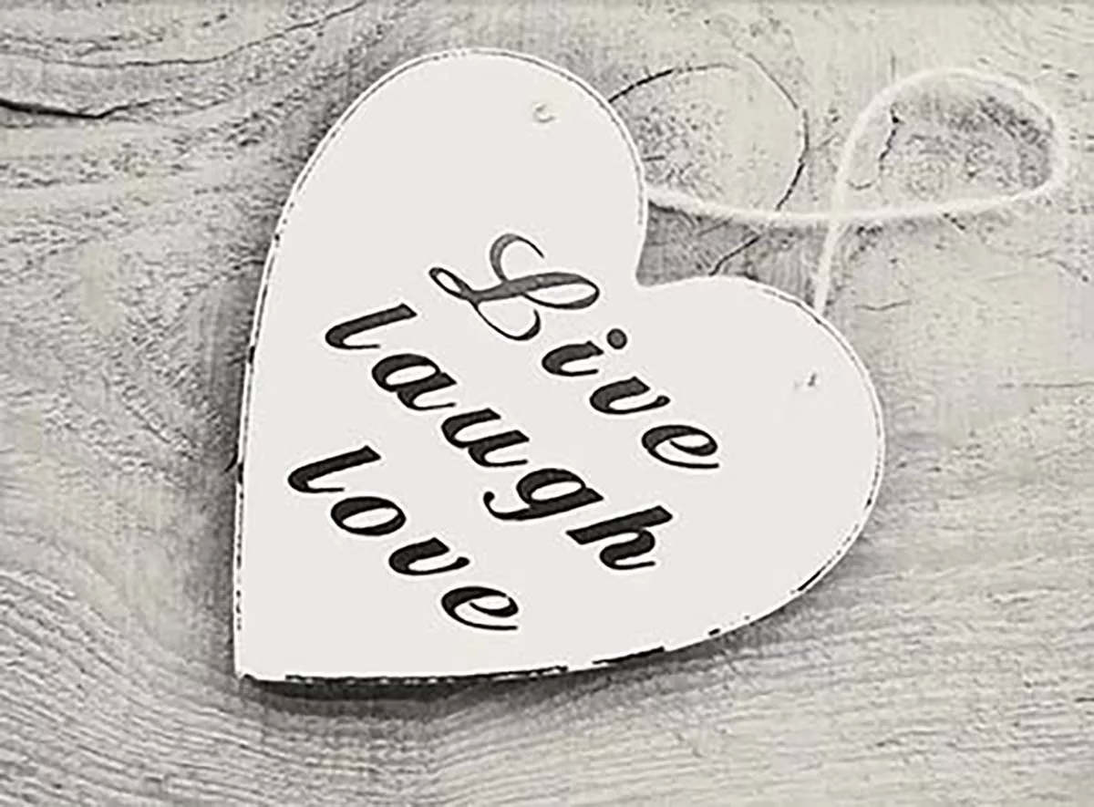 Heart-shaped wood sign with "Live Laugh Love" text on a rustic wooden background.