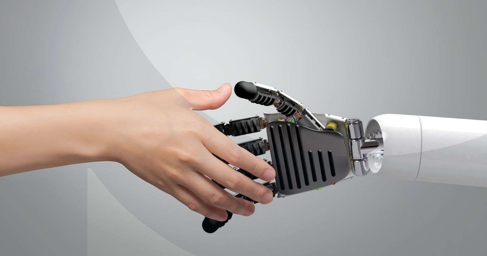 Human hand shaking a robot hand against a gray background