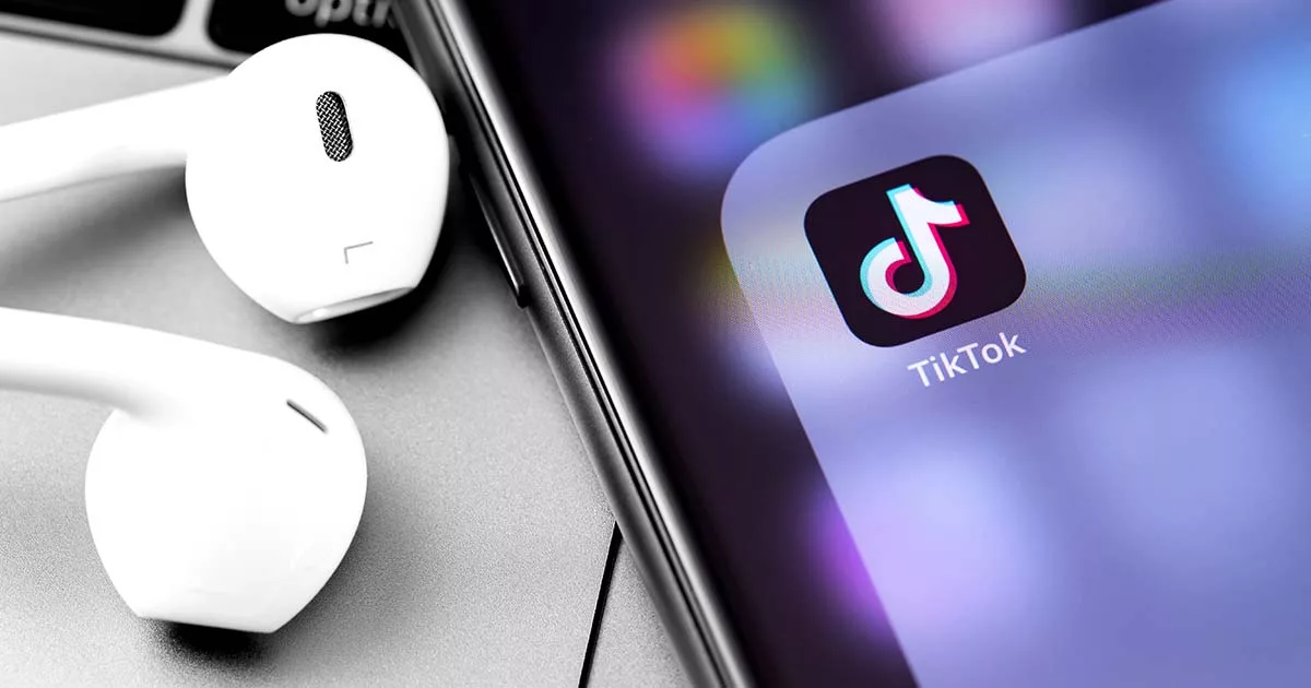 Smartphone displaying TikTok app icon next to white earphones
