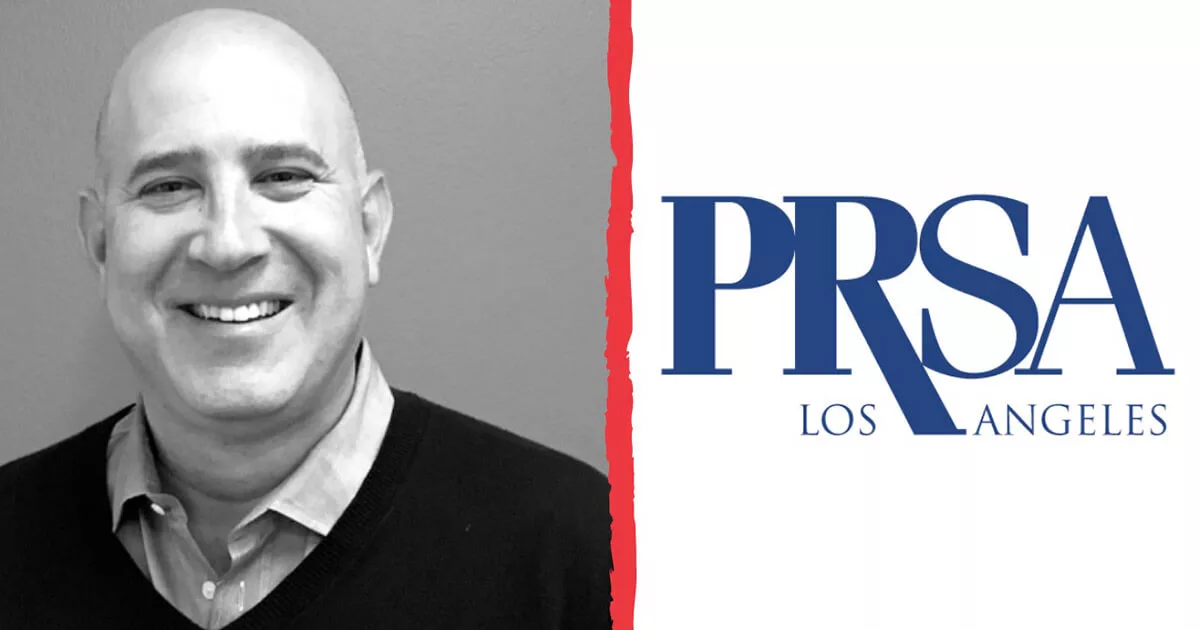 Smiling bald man in sweater next to blue PRSA Los Angeles logo on white background.