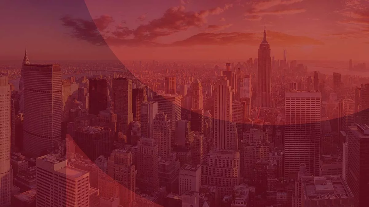 New York City skyline at sunset with skyscrapers silhouetted against a colorful sky.