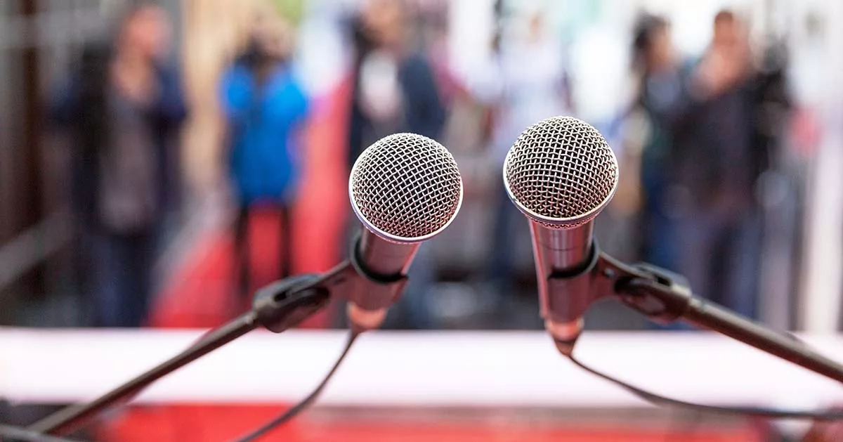 Two microphones on a podium with blurred audience in the background