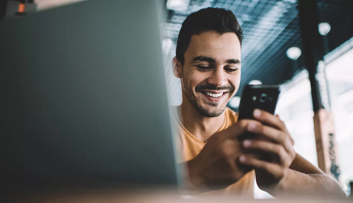 Smiling man using smartphone at cafe