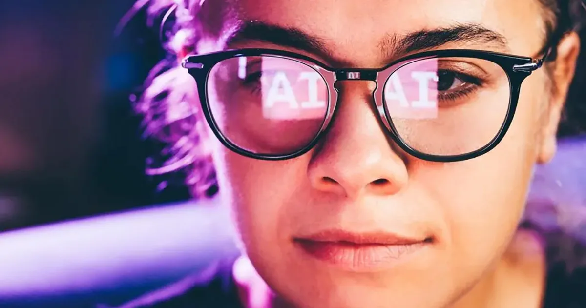 Person wearing glasses with "AI" reflected