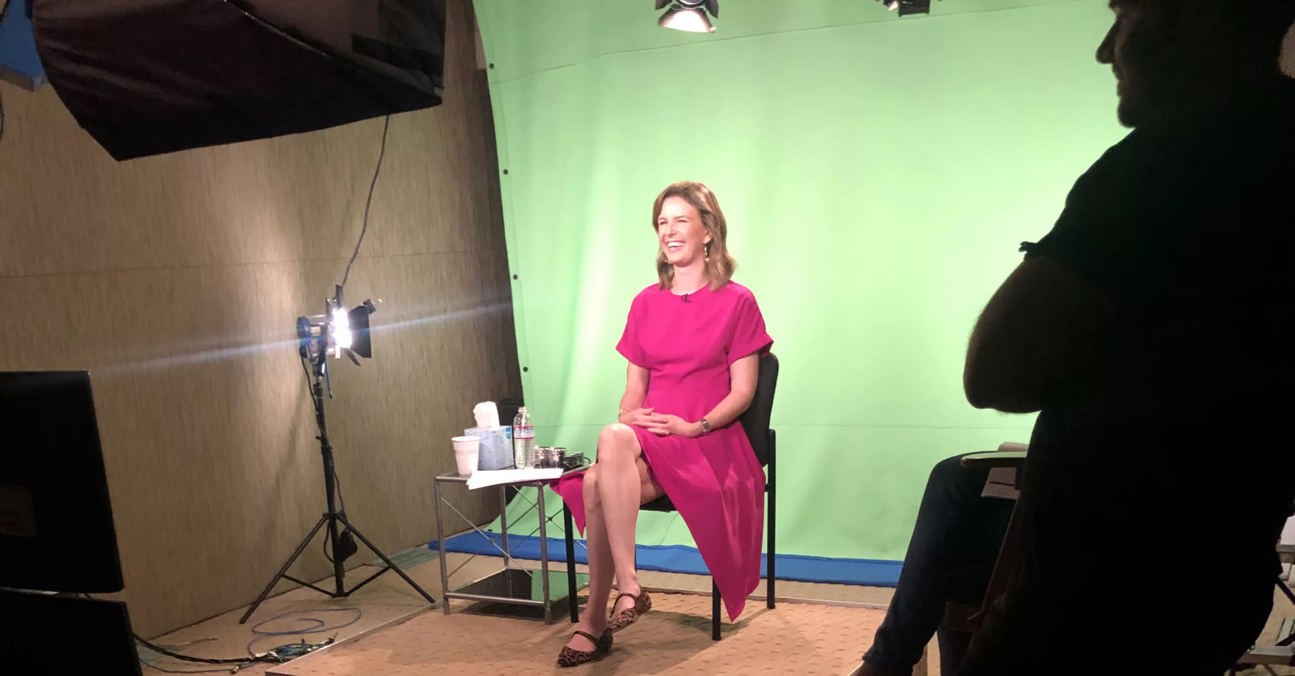 Woman in pink dress on set with green screen