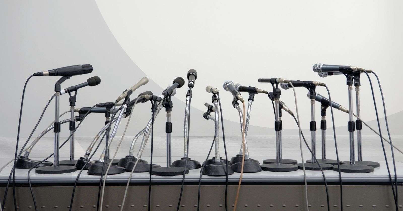 A group of microphones on a podium facing towards a gray background
