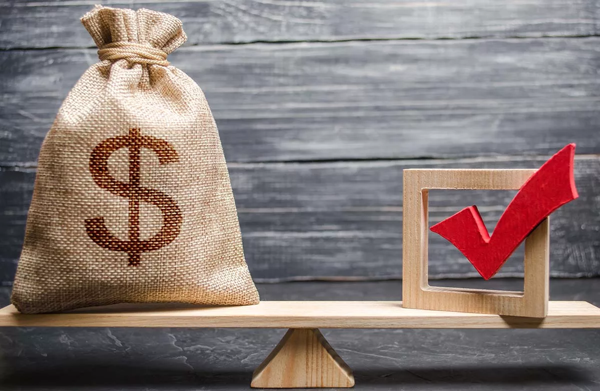 Burlap sack with dollar sign balanced on a plank