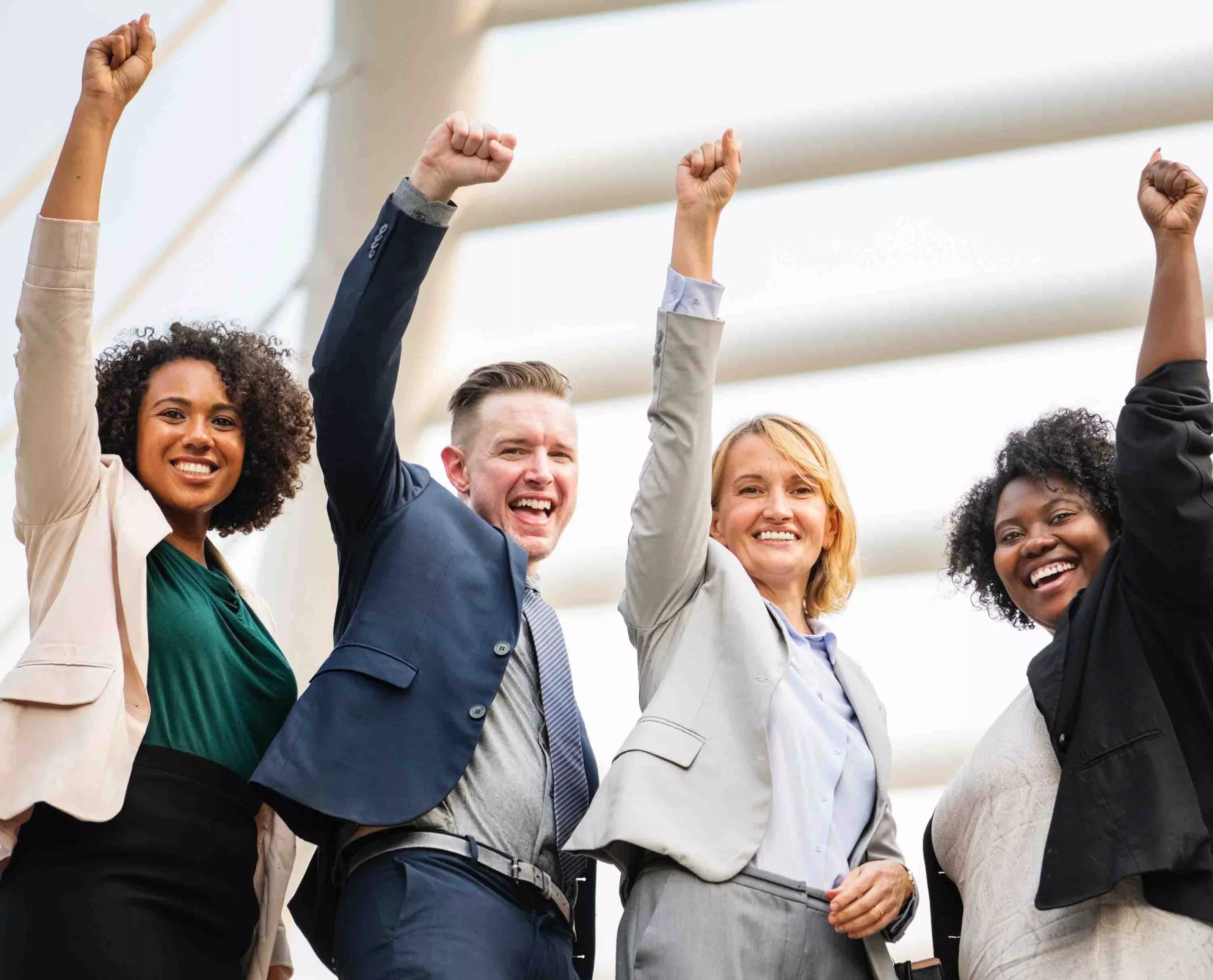 Diverse team celebrating success with raised fists outdoors