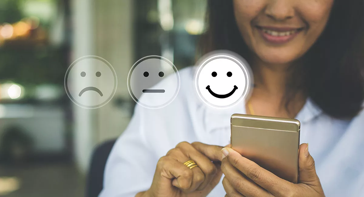 Woman using smartphone with three emoticons: sad