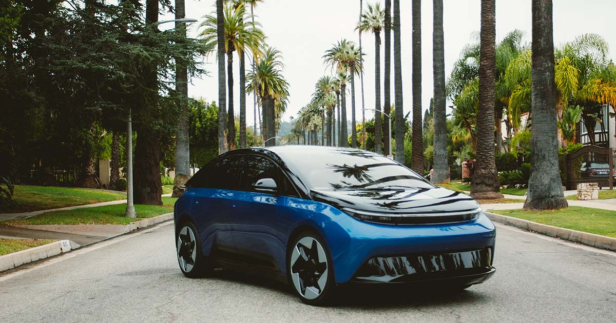 Sleek electric car driving down a palm tree-lined street