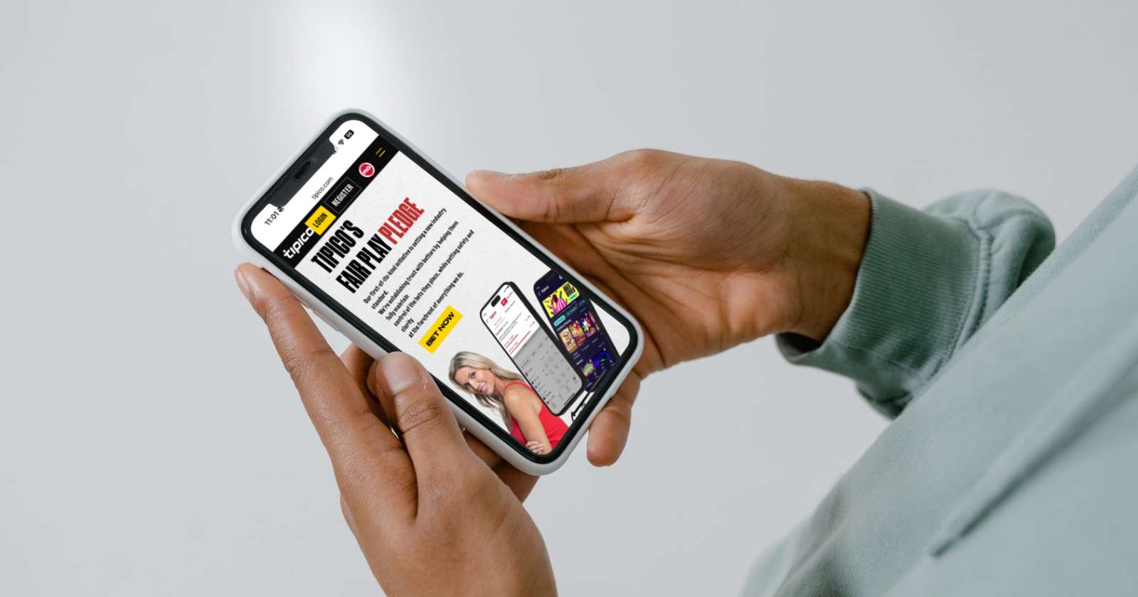 Person holding smartphone displaying online betting app with images of sports