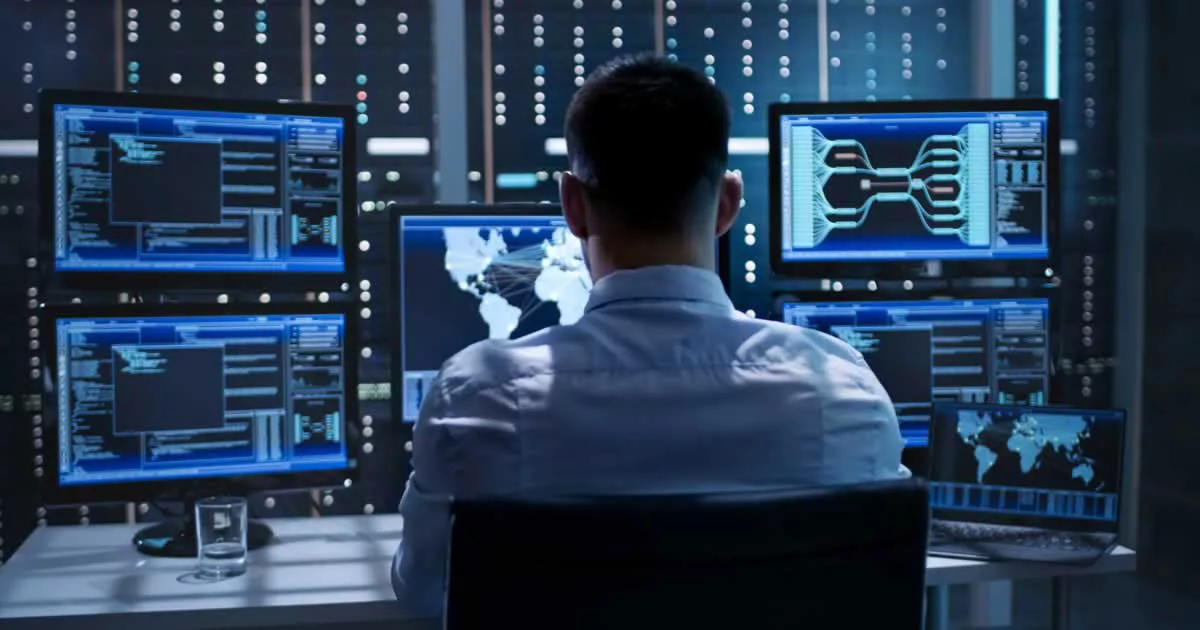 Person analyzing data on multiple computer screens in a server room; focus on cybersecurity and global network maps.