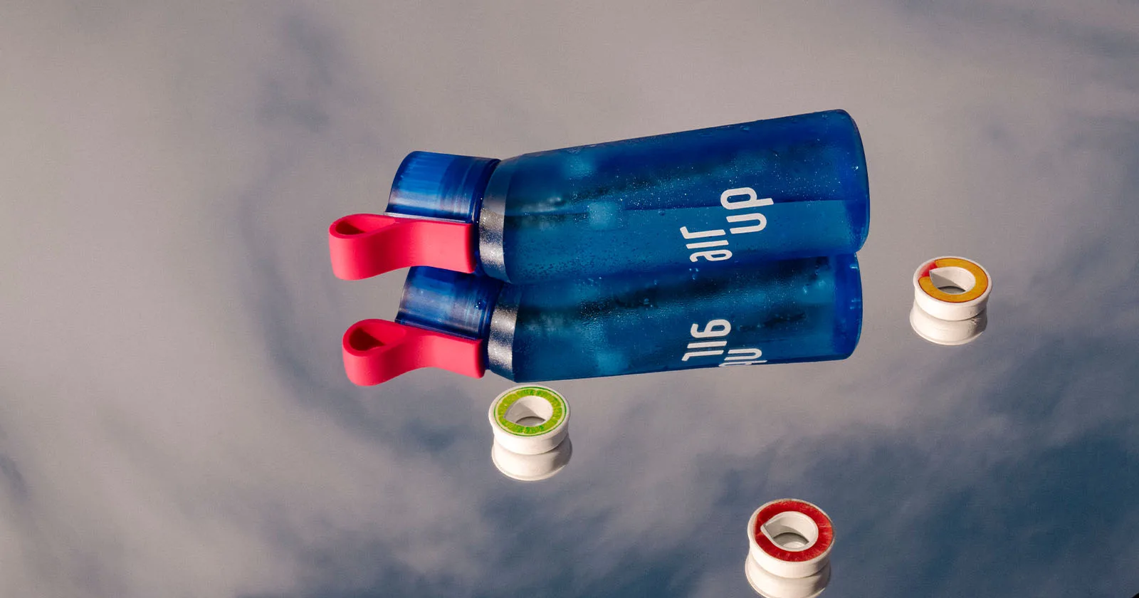 Blue water bottles with pink handles floating on a reflective surface