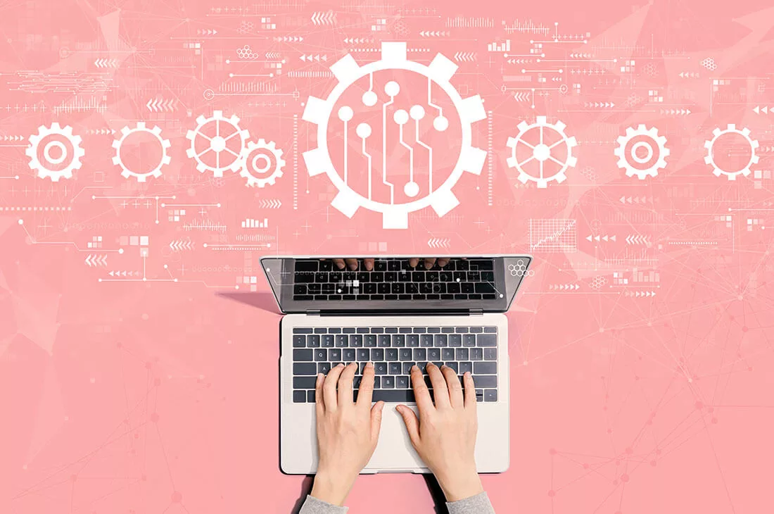 Hands typing on a laptop with abstract gears and circuit symbols on a pink background