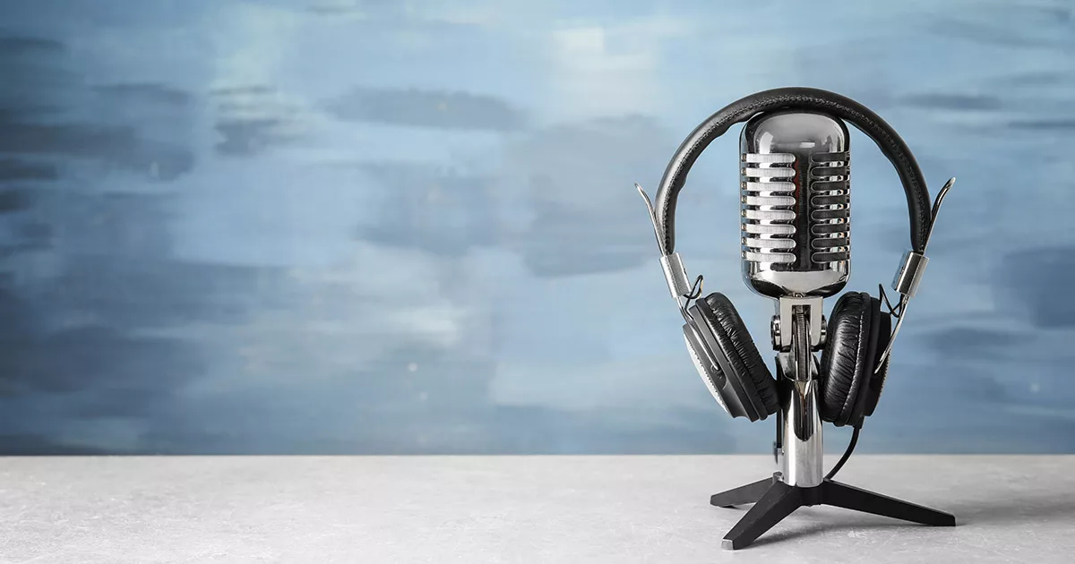 Vintage microphone with headphones against a blue background