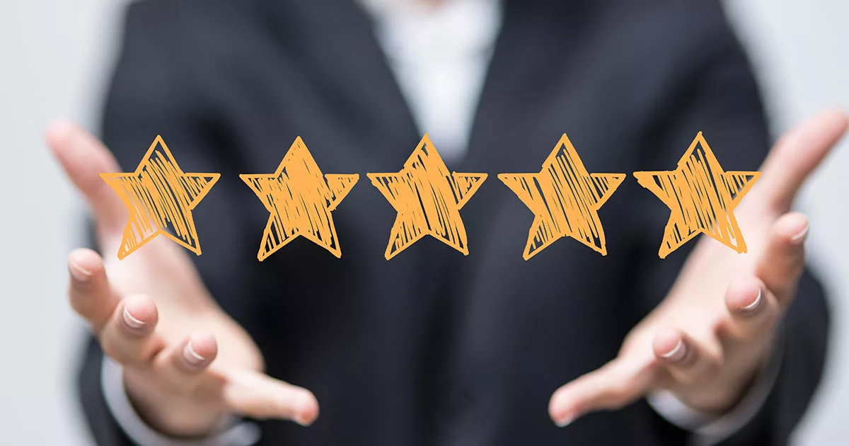 Hands presenting five gold stars on a blurred background
