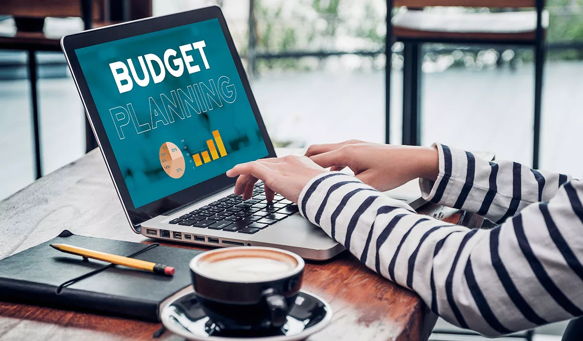 Person typing on laptop with budget planning graphics