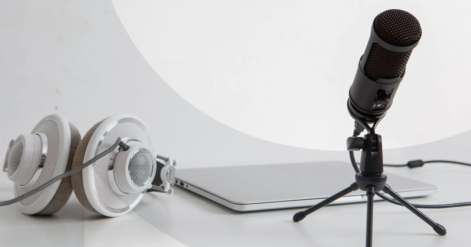 A microphone, laptop, and headset sitting next to each other against a white background.
