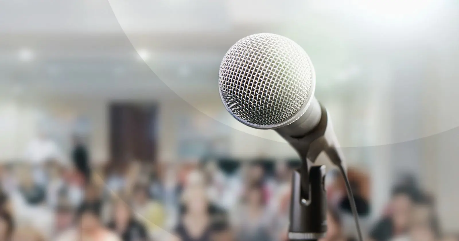 Microphone on a stage in front of a crowded room.