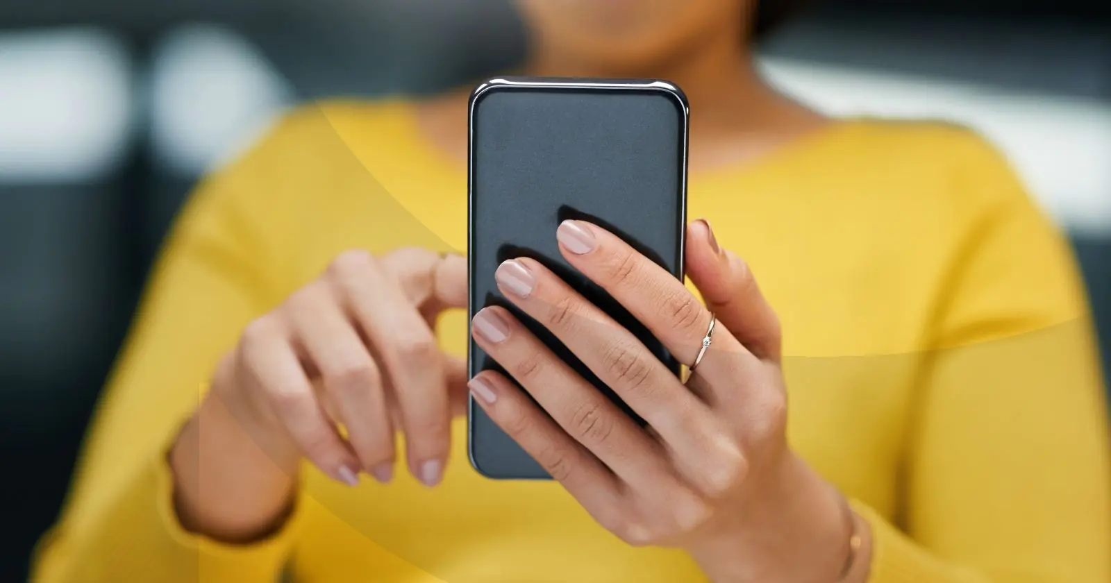 Woman in a yellow shirt scrolling on her phone
