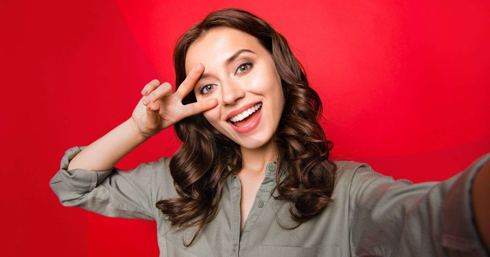 Woman taking a selfie with a red background.