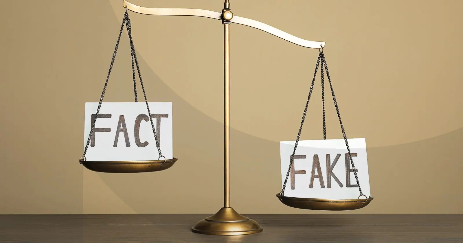 Scales balancing two notecards that say "fact" and "fake" respectively