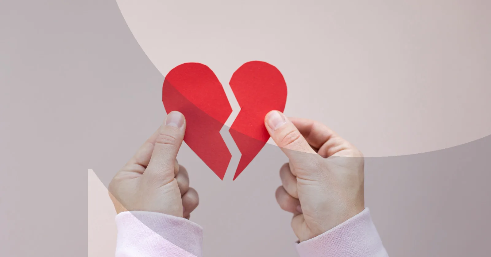 Hands holding a broken red paper heart