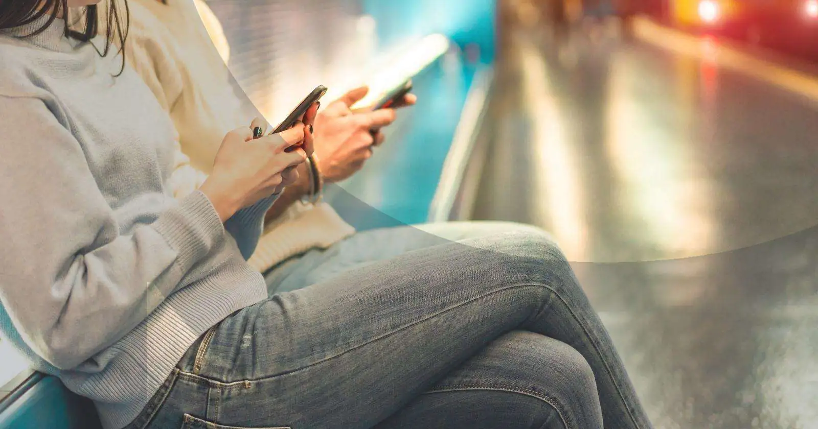 People sitting on a subway bench using smartphones