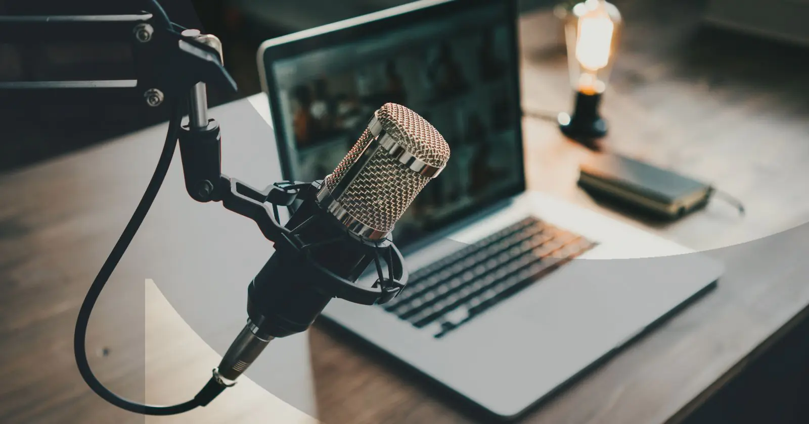 Podcasting setup with a microphone and laptop on a wooden desk