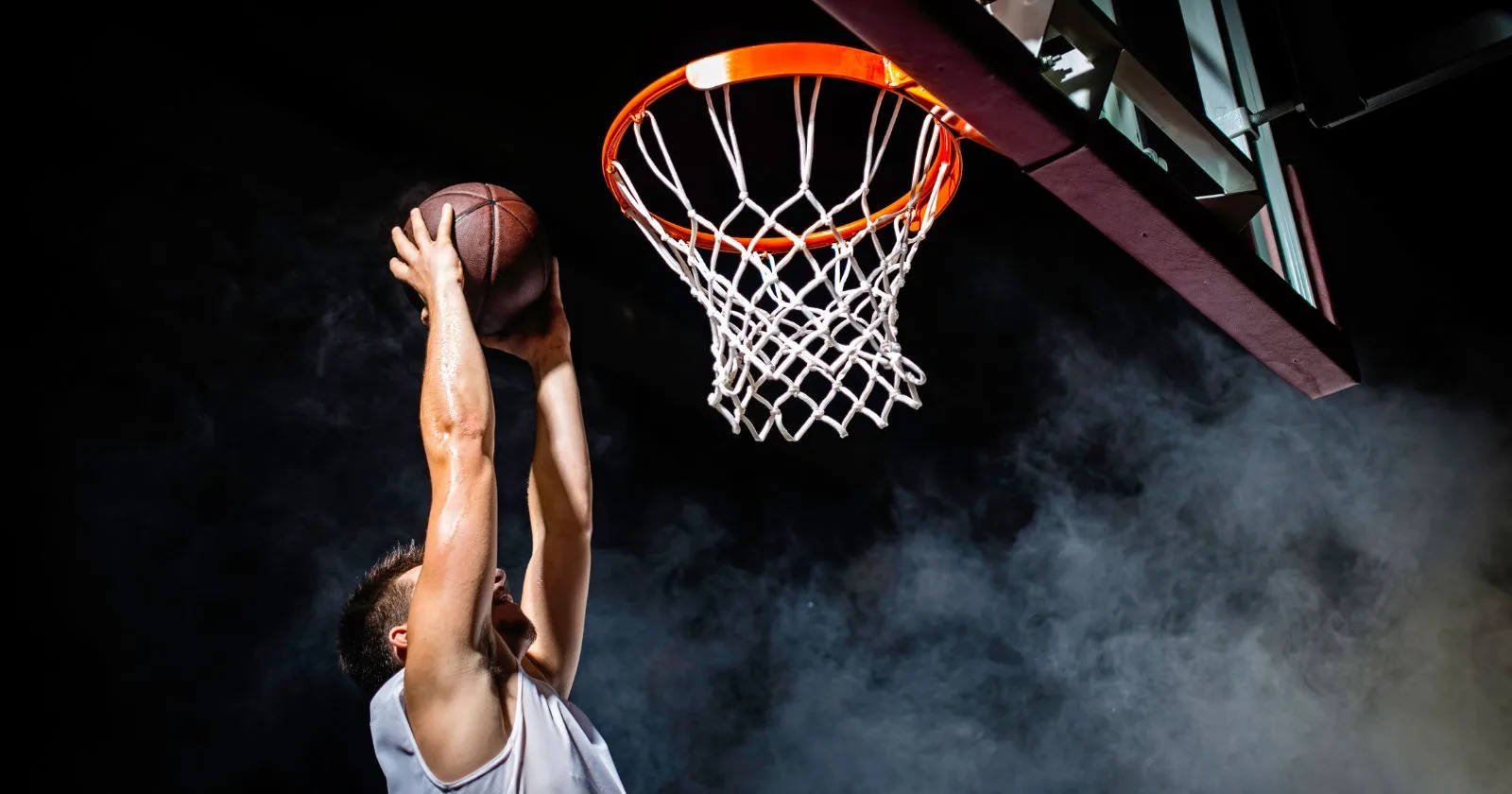 Basketball player executing a slam dunk in mid-air against a dramatic