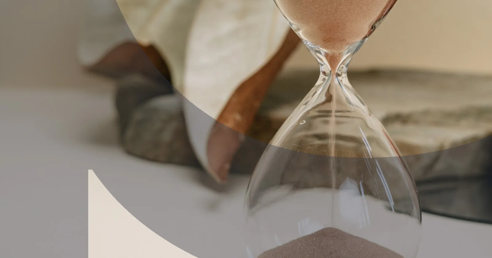 Sand flowing through a glass hourglass on a textured stone surface
