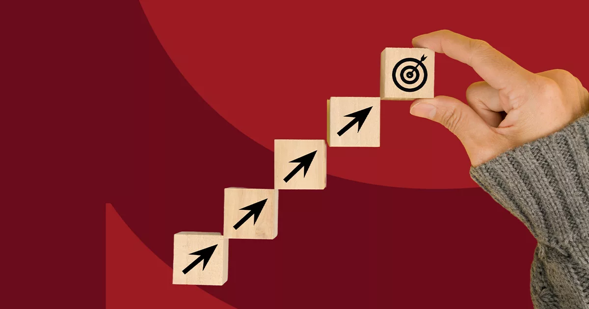 Hand placing target block atop a staircase of arrow blocks on red background