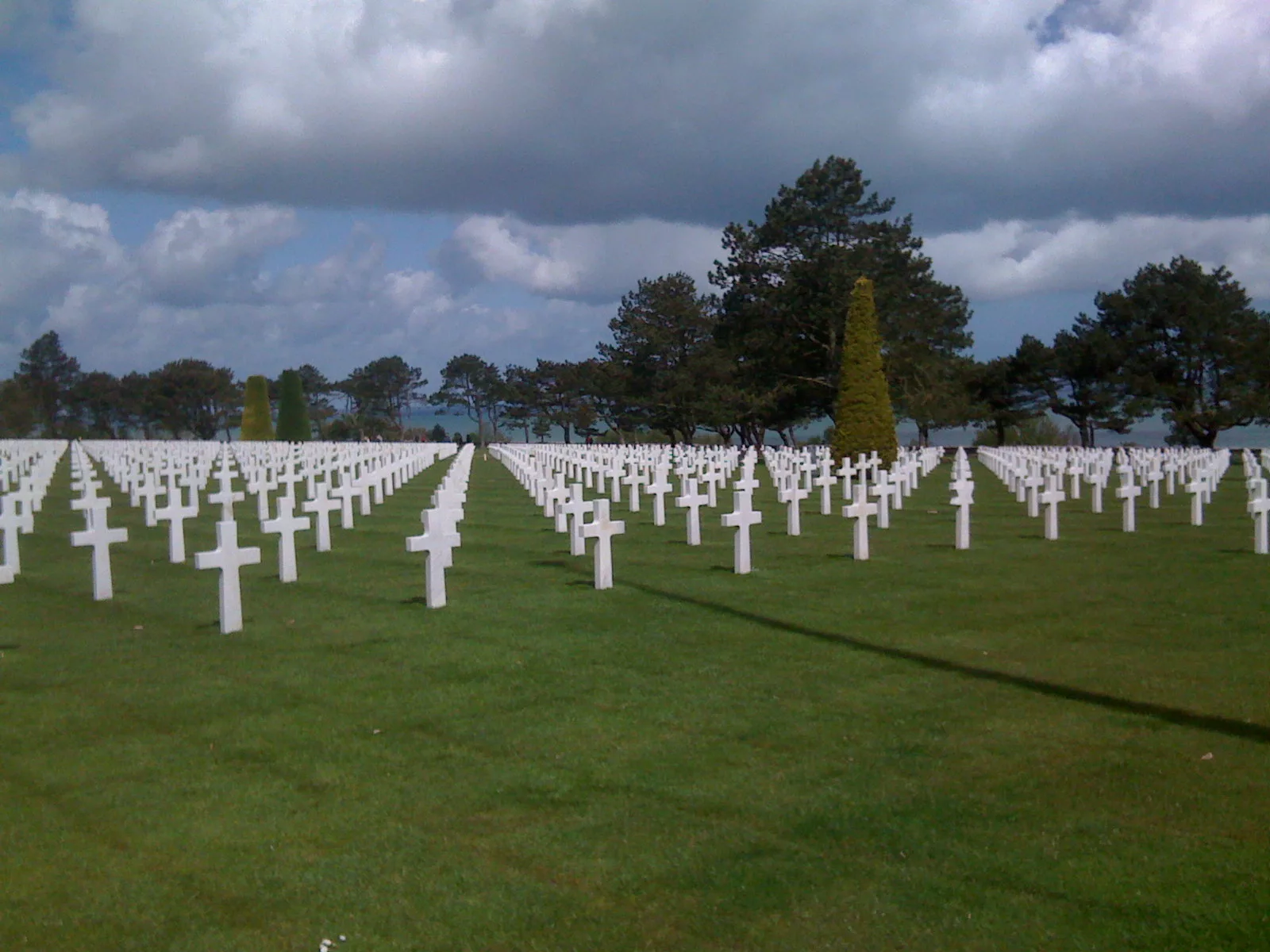 Rows of white crosses in a military cemetery under a cloudy sky
