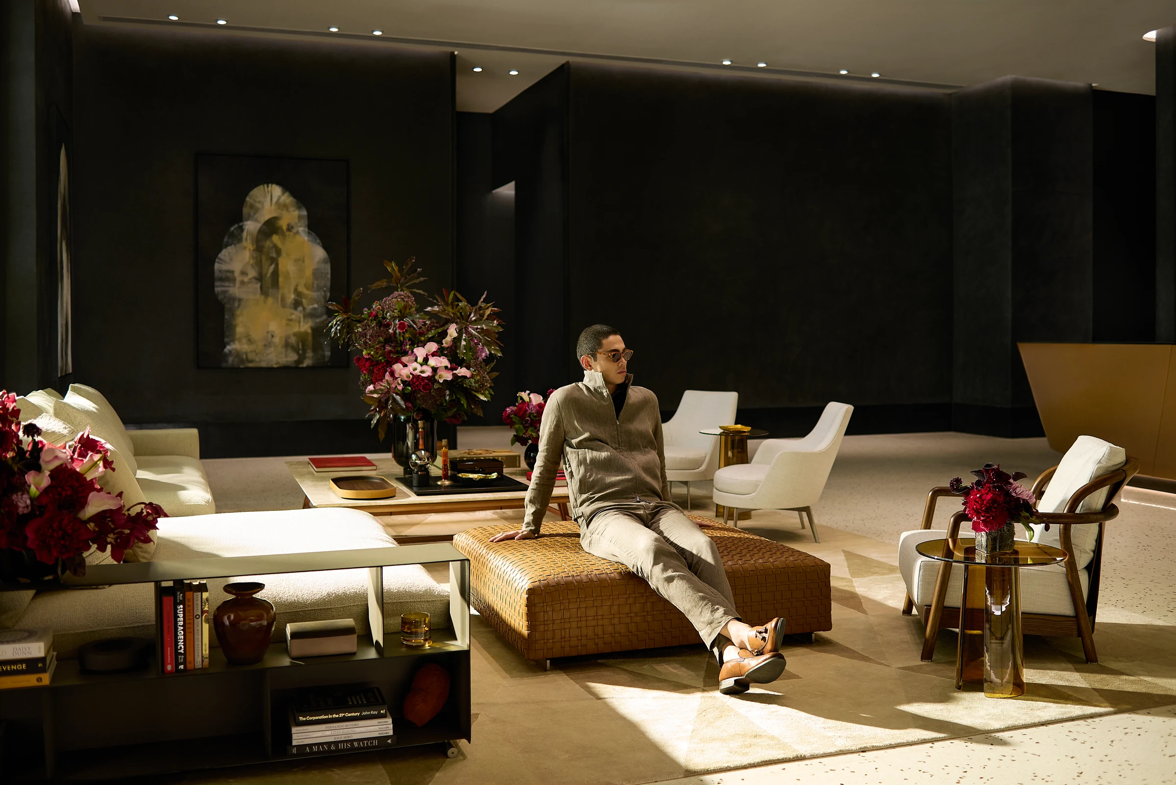 A resident seated in an interior lounge with flowers and dining tables.