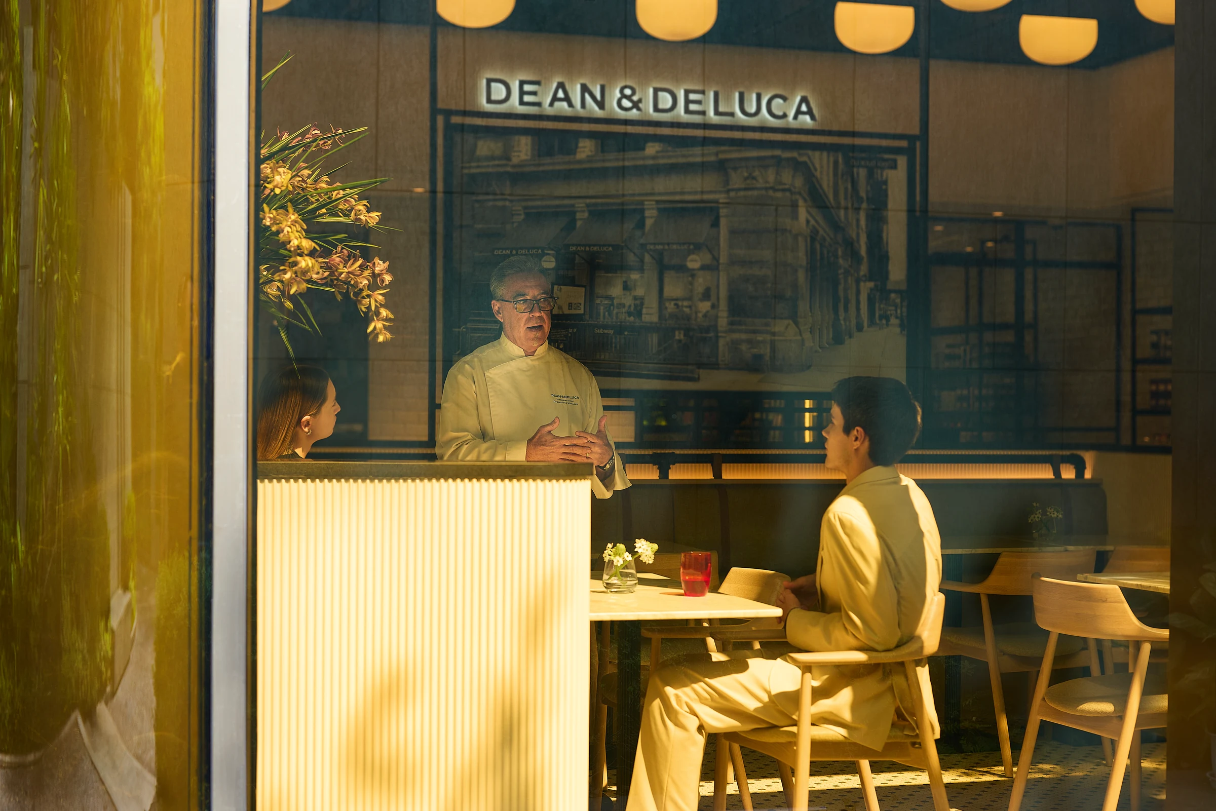 A DEAN & DELUCA cafe counter with a customer seated at a table.