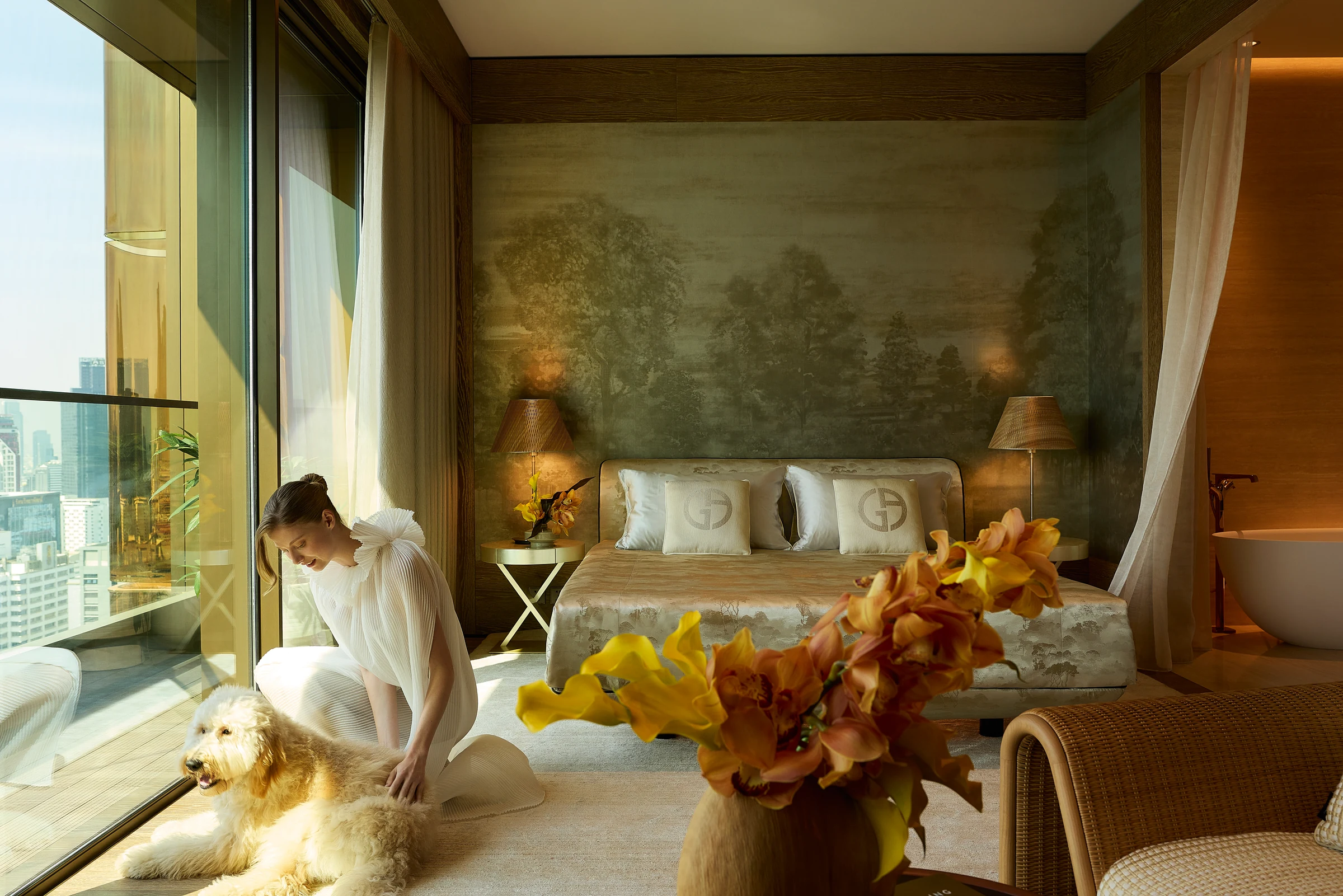 A Sunrise Residence bedroom with a city view and floral arrangement.