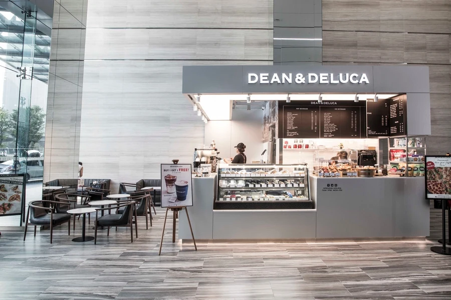 A DEAN & DELUCA cafe counter with tables in a spacious indoor setting.