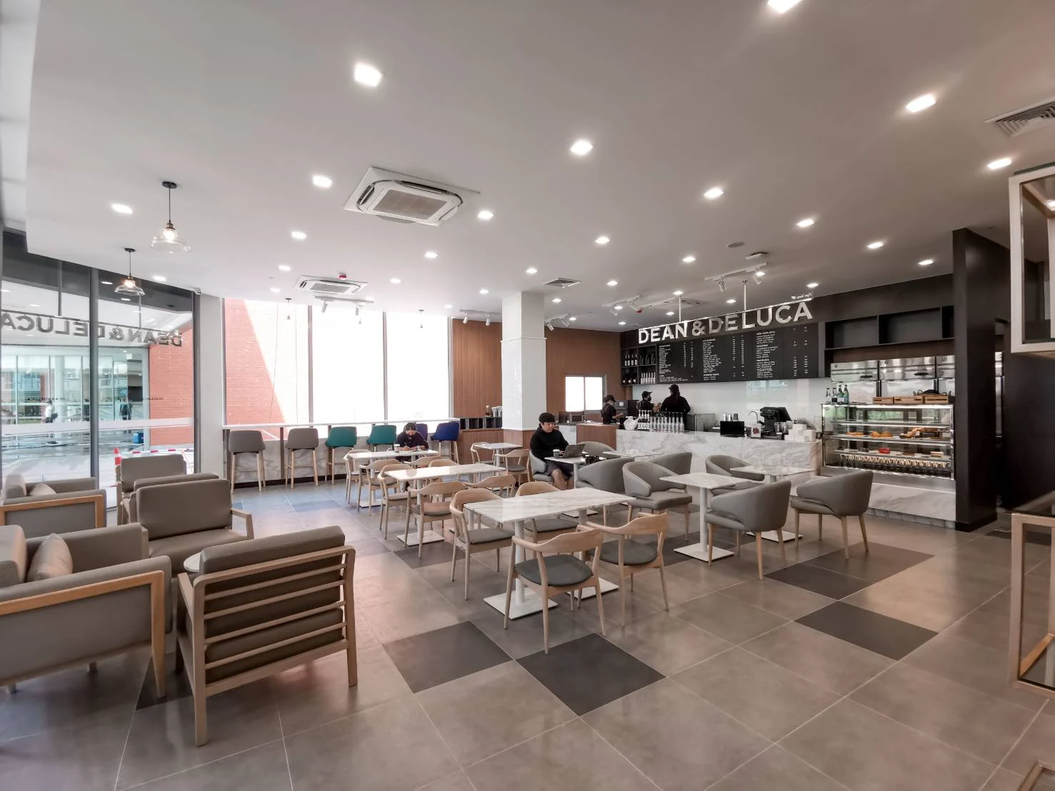 A DEAN & DELUCA cafe interior with dining tables and large windows.