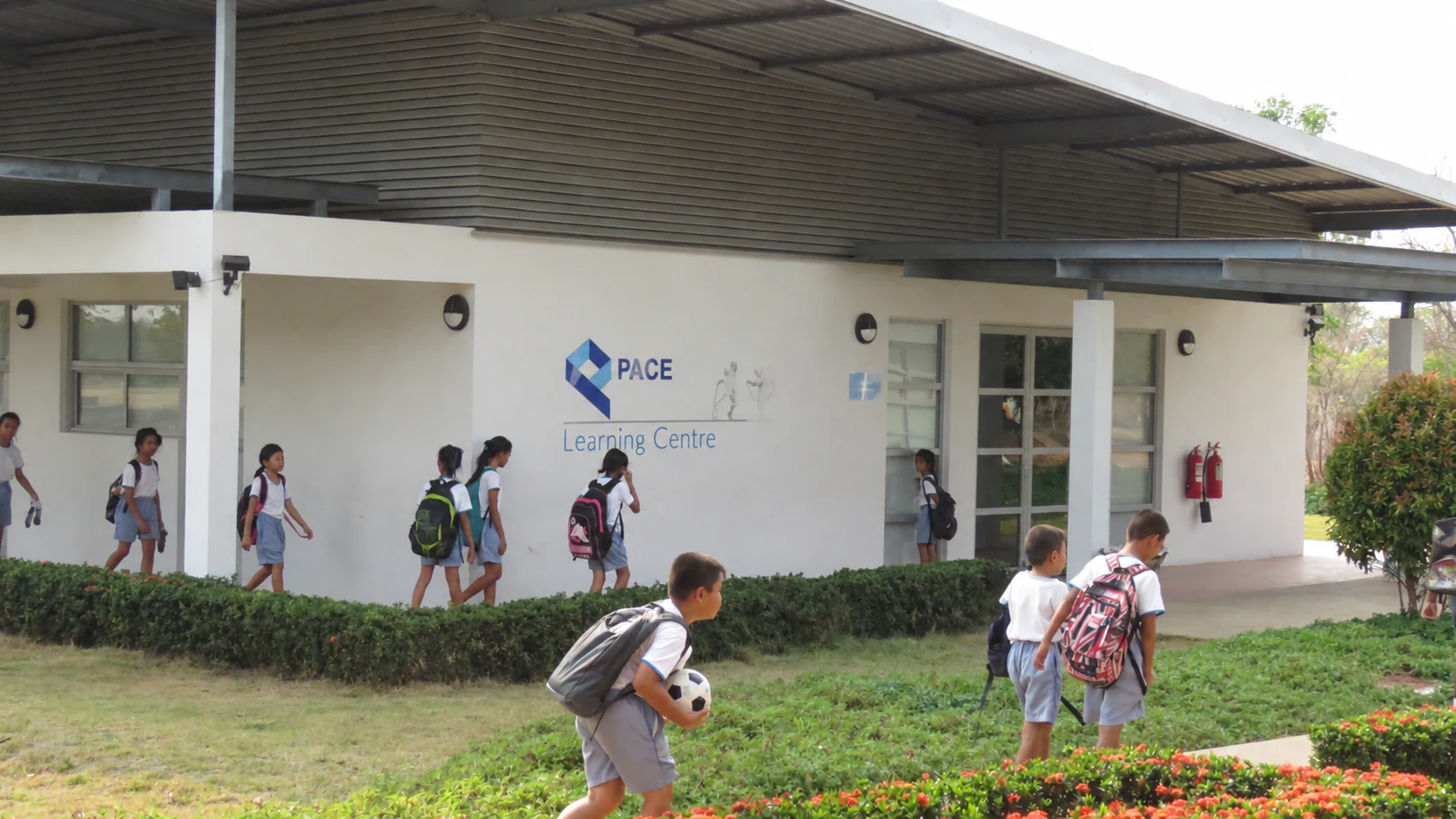 Children outside a school building bearing the PACE name.